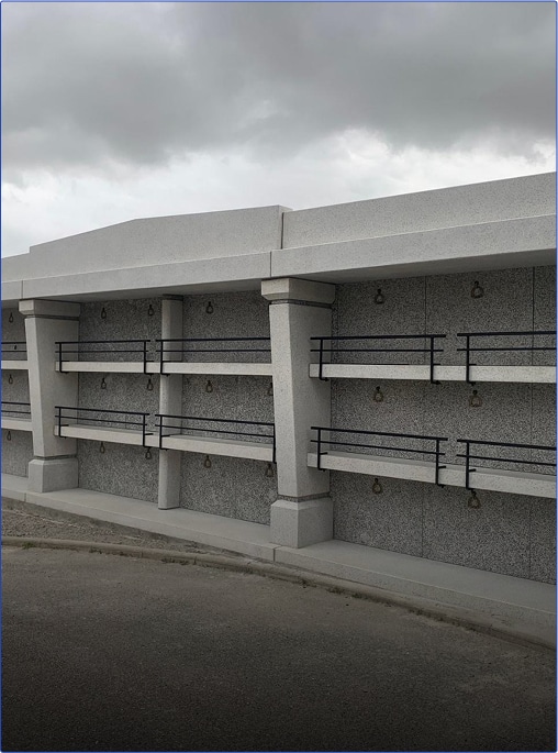 Mur de mausolées moderne sous un ciel nuageux.