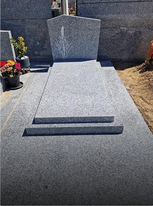 Tombe en granit avec fleurs à proximité.