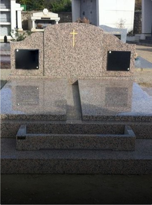 Tombe en granit avec croix et plaques noires.
