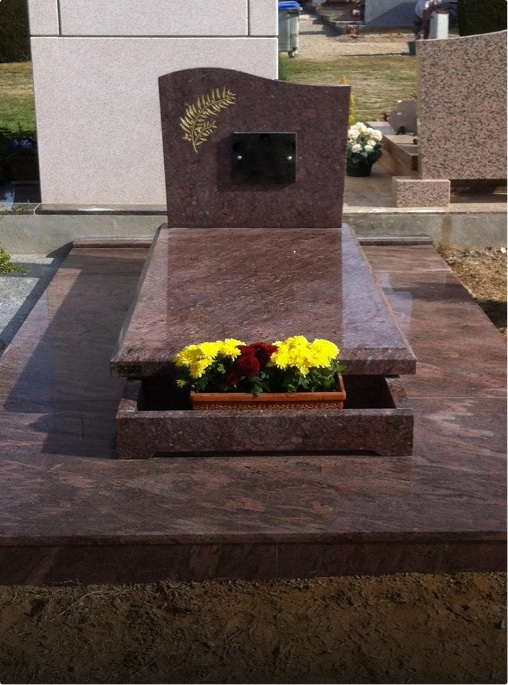 Tombe avec fleurs sur un monument en granit.